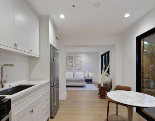 a kitchen with white cabinets and a table and a bed at Dume Malibu in Malibu