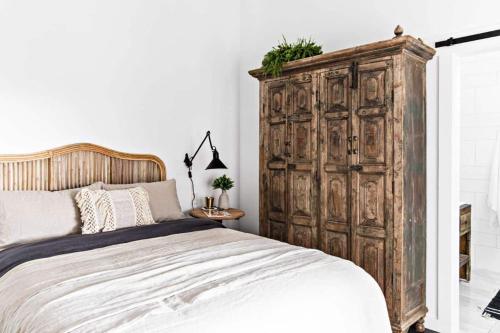 a bedroom with a large wooden cabinet next to a bed at Soul of Gerringong Cottage in Gerringong