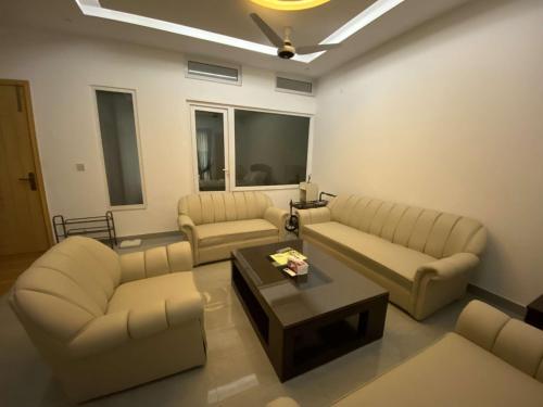 a living room with couches and a coffee table at Airport Layover Family Lodge in Islamabad