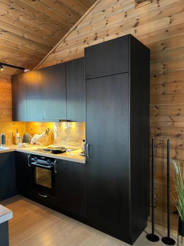 a kitchen with black cabinets and a stove at Fantastic view, great holiday in Tjørhom Sirdal in Haugen