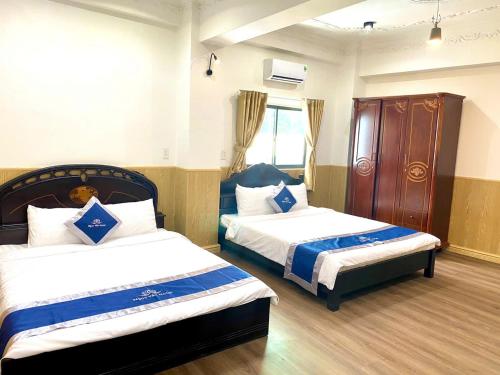 a hotel room with two beds and a window at Khách Sạn Và Nhà Hàng Ngọc Yến 5 Vĩnh Long in Vĩnh Long