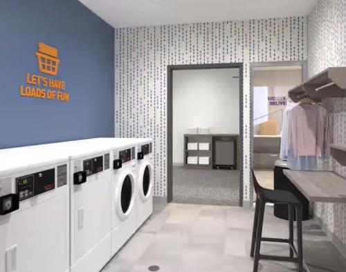 a laundry room with a washing machine and a table at Home2 Suites By Hilton Syracuse Liverpool Airport Area in Liverpool