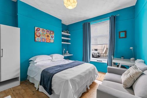 a blue bedroom with a bed and a couch at Arundel House - Parkview with free parking in Plymouth