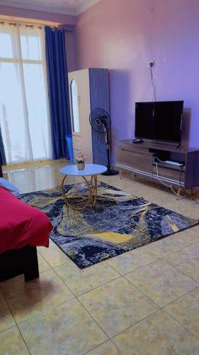 a living room with a table and a tv at Comfortable home in Kampala