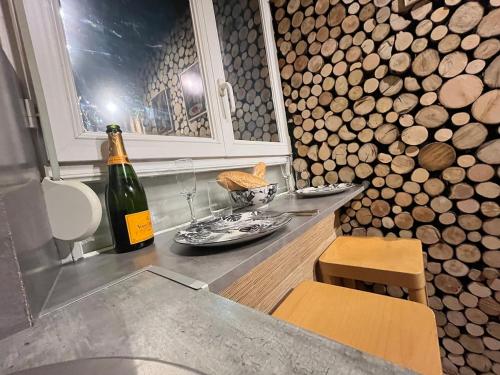 a bottle of wine sitting on a counter next to a room with logs at Jungle Room Jacuzzi Ambiance Tropicale in Épernay
