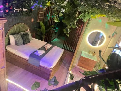 a bedroom with a bed and a round mirror at Jungle Room Jacuzzi Ambiance Tropicale in Épernay