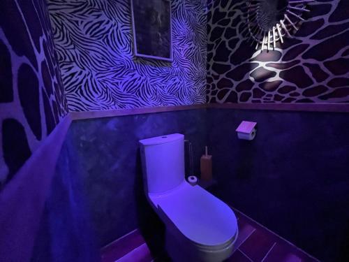 a purple bathroom with a toilet in a room at Jungle Room Jacuzzi Ambiance Tropicale in Épernay