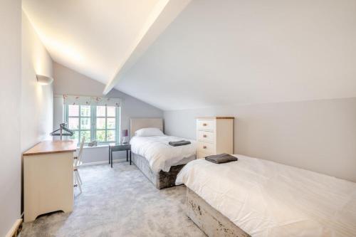 a bedroom with two beds and a desk in it at Marlpit House in Coltishall