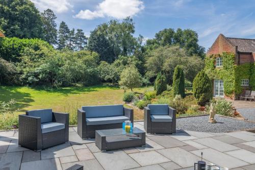 a patio with chairs and a table in front of a yard at Marlpit House in Coltishall