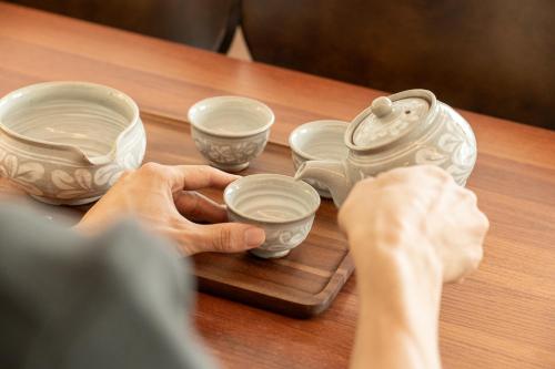 a person is holding cups on a wooden table at 15sec from station cozy house in Seoul