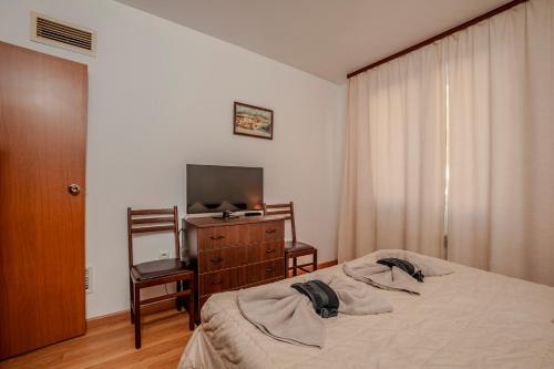 a bedroom with a bed and a dresser and a television at Holiday home with indoor fireplace in Pamporovo