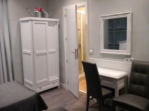 una stanza con tavolo, specchio e armadietto bianco di Hostal Don Alfonso a Madrid