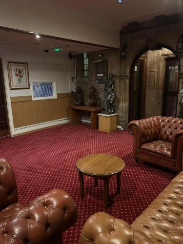 a living room with leather furniture and a table at Westone Manor Hotel in Northampton