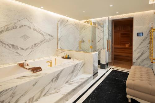 a bathroom with white marble walls and a tub at Ayan Zalaat in Ulaanbaatar