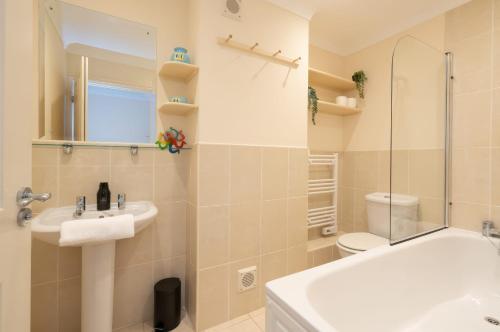 a bathroom with a sink and a tub and a toilet at Beach House in Bembridge