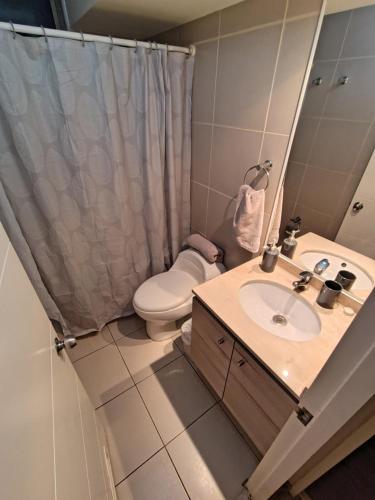 Un baño con lavabo, inodoro y espejo. en Montemar vista, en Concón