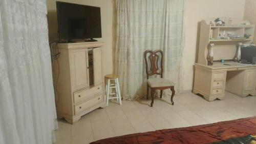 Zimmer mit einem TV, einem Schreibtisch und einem Stuhl in der Unterkunft Alojamiento OLSI in Torreón