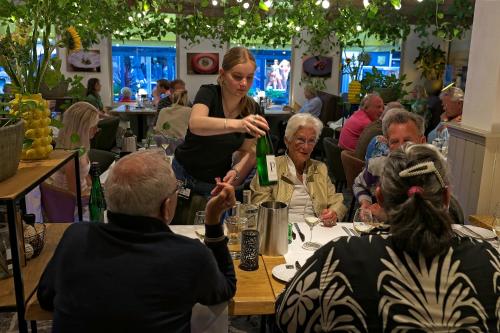 a woman standing at a table holding a bottle of wine at Hotel Nap in West-Terschelling