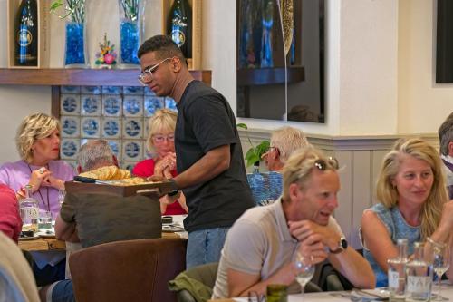 a man holding a tray of food on a plate at Hotel Nap in West-Terschelling