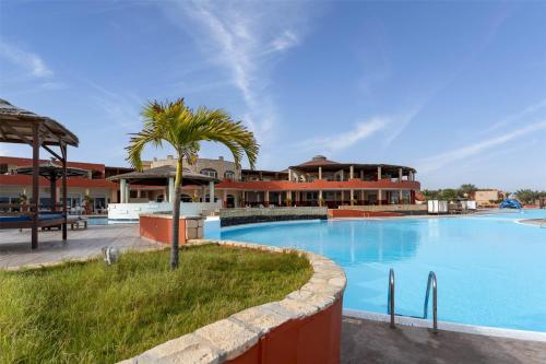 a large swimming pool with a palm tree next to a building at Occidental Boa Vista Beach in Rabil