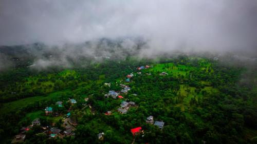 an aerial view of a green hill with clouds at Jaadooghar Madcap Mudhouse in Palāhu