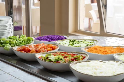 a buffet with bowls of vegetables on a counter at Occidental Boa Vista Beach in Rabil