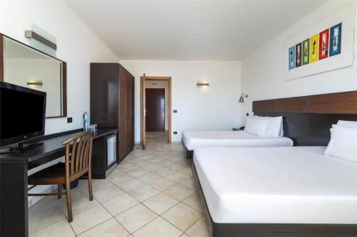 a hotel room with two beds and a desk and a television at Occidental Boa Vista Beach in Rabil