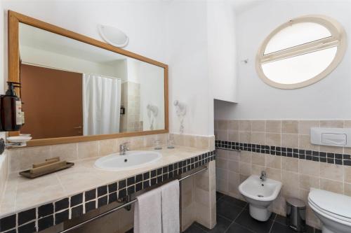 a bathroom with a sink and a toilet and a mirror at Occidental Boa Vista Beach in Rabil