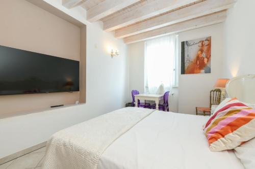 a bedroom with a white bed with a flat screen tv at Le Rêve - Lake view rooms in Sirmione