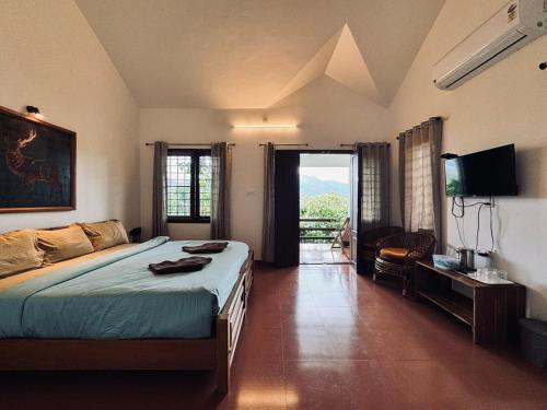 a bedroom with a bed and a television and a couch at Dhanagiri Homestay Wayanad in Vythiri