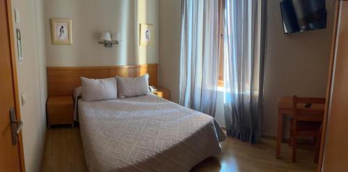 a small bedroom with a bed and a window at Hotel Castilla in Cáceres