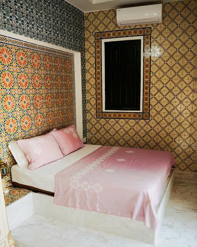 a bedroom with a pink bed and a wall at DAR EL HAMRA in Mahdia