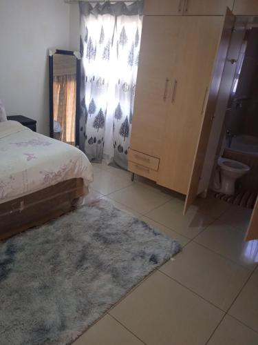a bedroom with a bed and a bathroom with a toilet at Tsoga OTirele guesthouse in Matrooster