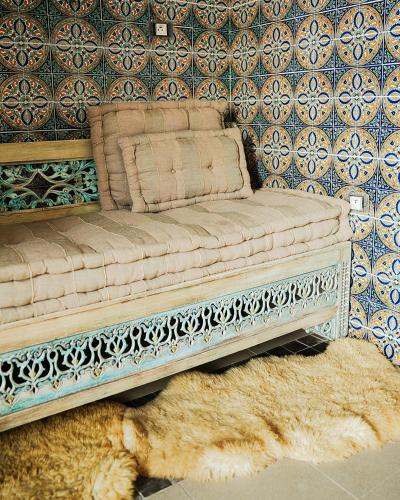 a couch sitting in front of a wall with a rug at DAR EL HAMRA in Mahdia