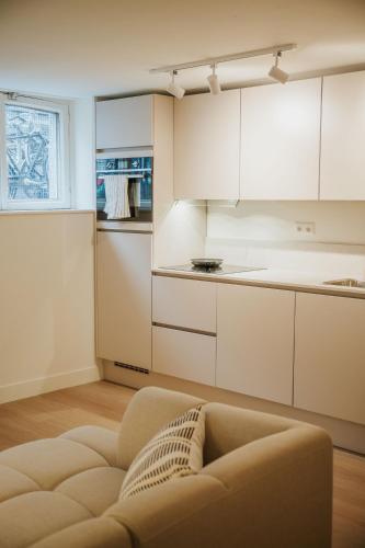 a kitchen with white cabinets and a couch at Naest - Authentic Escapes City House Nijmegen in Nijmegen