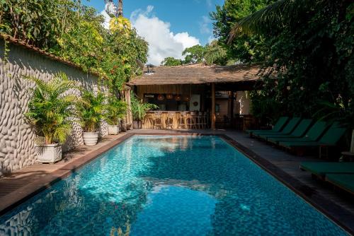 a swimming pool with green chairs and a building at Pousada Cajueiro Trancoso in Trancoso
