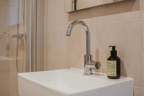 a bottle of soap sitting on top of a sink at Naest - Authentic Escapes City House Nijmegen in Nijmegen
