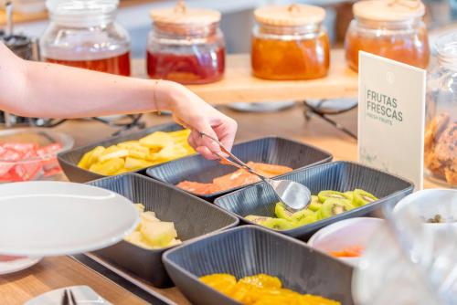 a person is serving food in containers on a buffet at Hotel Port Salins by Pierre & Vacances in Empuriabrava