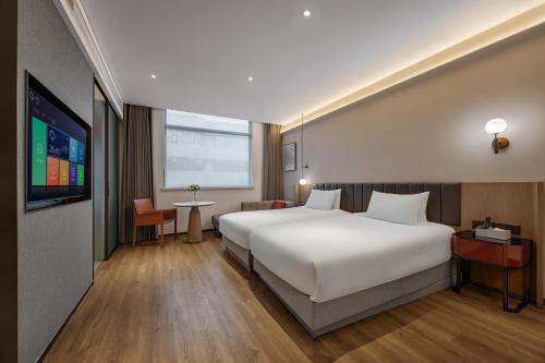 a bedroom with a large white bed and a tv at 上海浦东机场华美达安可酒店-免费提供24小时浦东机场班车十分钟到达候机楼出发层 in Shanghai