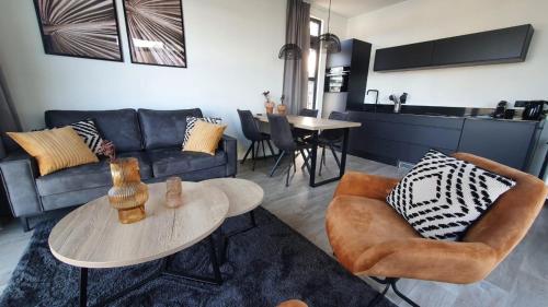 シント・マールテンスデイクにあるVakantiepark de Zeeuwse Parel - De Witte Parelのソファと椅子とテーブルのあるリビングルーム