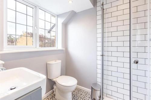 a white bathroom with a toilet and a sink at Homely 4 Bedroom House Addlestone in Addlestone