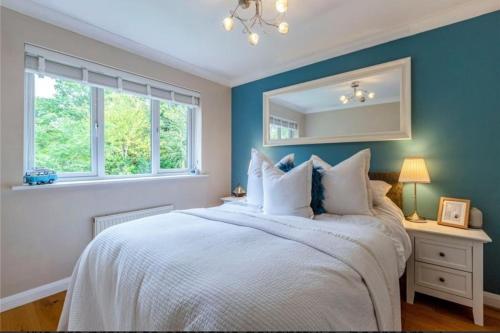 a bedroom with a white bed with a mirror at Homely 4 Bedroom House Addlestone in Addlestone