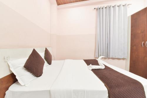 1 dormitorio con cama blanca y almohadas marrones en Arya Inn, en Jaipur
