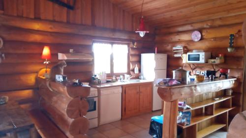 a kitchen in a log cabin with a sink and a refrigerator at Le Domaine de la Vergnolle in Roches