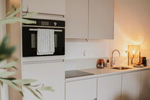 a kitchen with white cabinets and a black oven at Naest - Authentic Escapes City House Nijmegen in Nijmegen