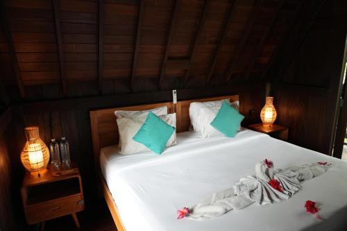 a bedroom with a bed with white sheets and blue pillows at Nunu Bali Eco Friendly Retreat in Canggu