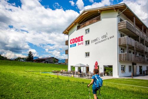 a man walking in front of a building at COOEE alpin Hotel Kitzbüheler Alpen in Sankt Johann in Tirol
