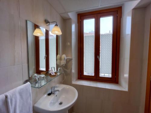 a bathroom with a sink and a mirror and a window at Hotel Castilla in Cáceres