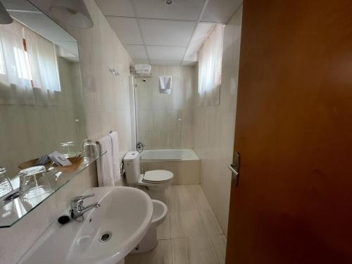 a white bathroom with a sink and a toilet at Hotel Castilla in Cáceres