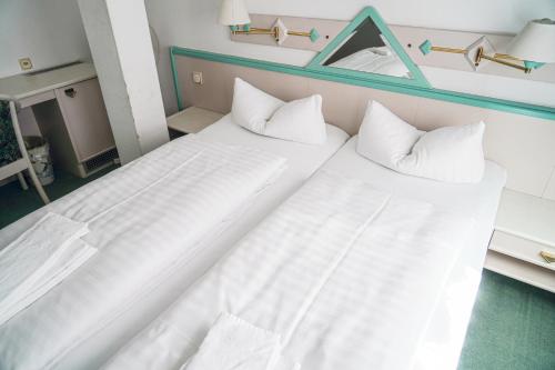 two beds in a hotel room with white sheets and pillows at Apart Hotel Leipzig Taucha in Taucha
